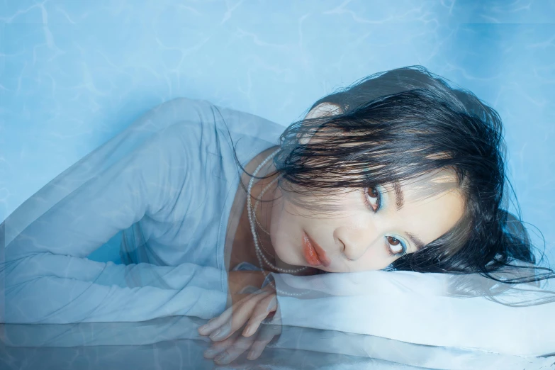 a woman lies down in a pool wearing a white dress