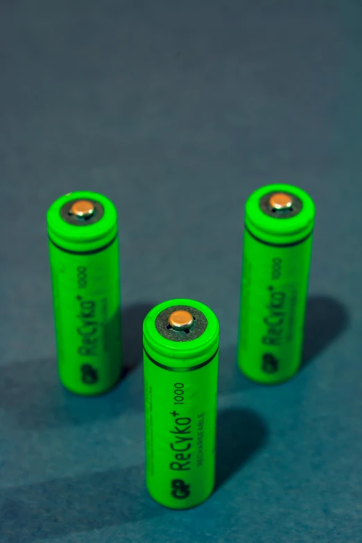 four green recharge batteries on blue surface