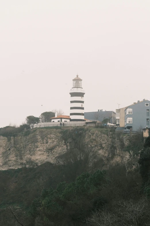 a large white and black lighthouse on top of a hill