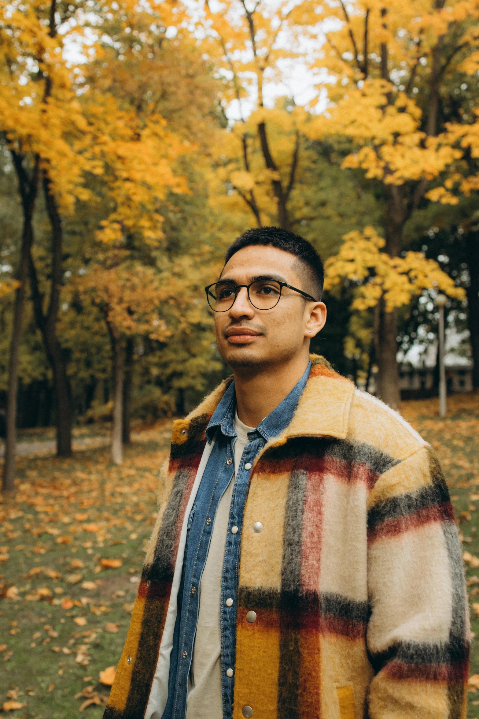 a man in glasses wearing a brown, red, black and yellow coat with an animal print lining the front