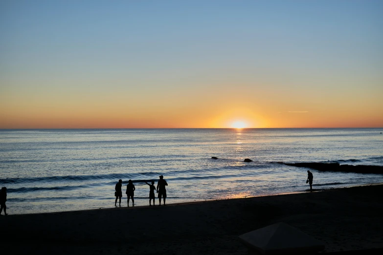 sunset over a beach with a lot of people in it