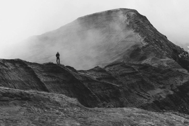 a man on top of a mountain with a mist rising from the summit