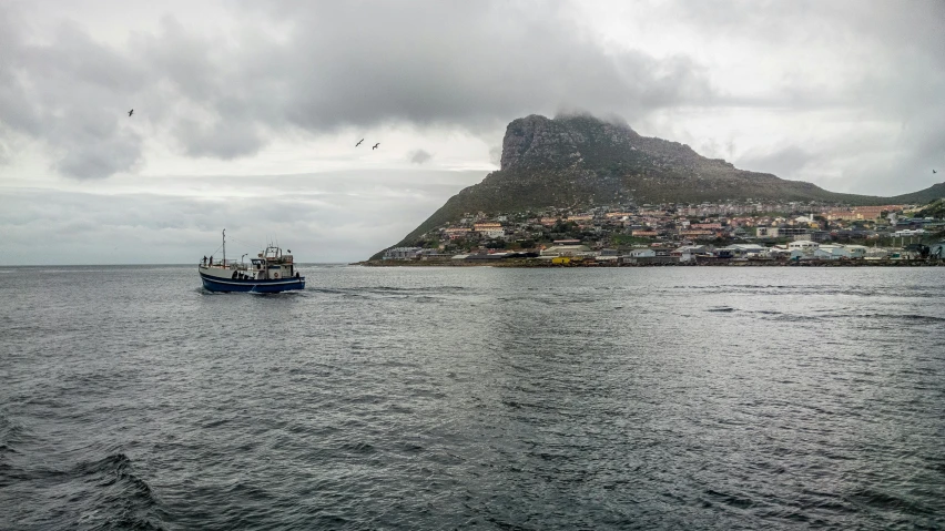 a boat traveling in a body of water near a mountain