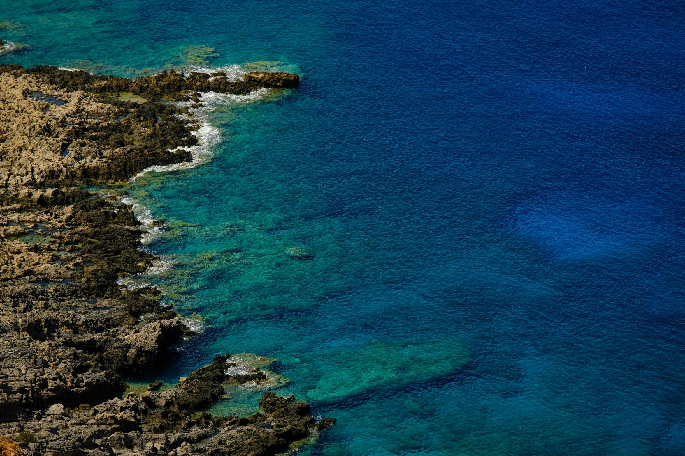 the water is blue and clear outside of the rocky shore