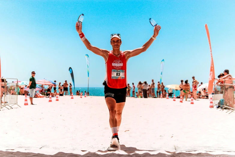 a man standing on a beach holding two arms up