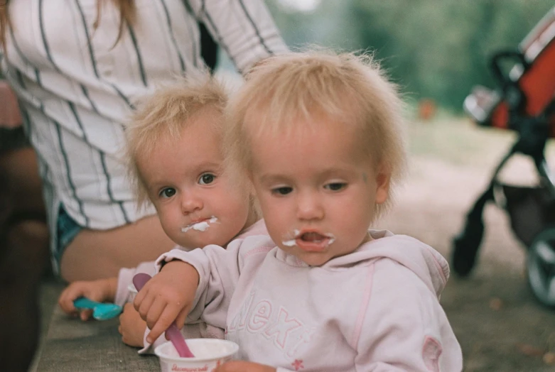 the child in front is holding soing up to her mouth