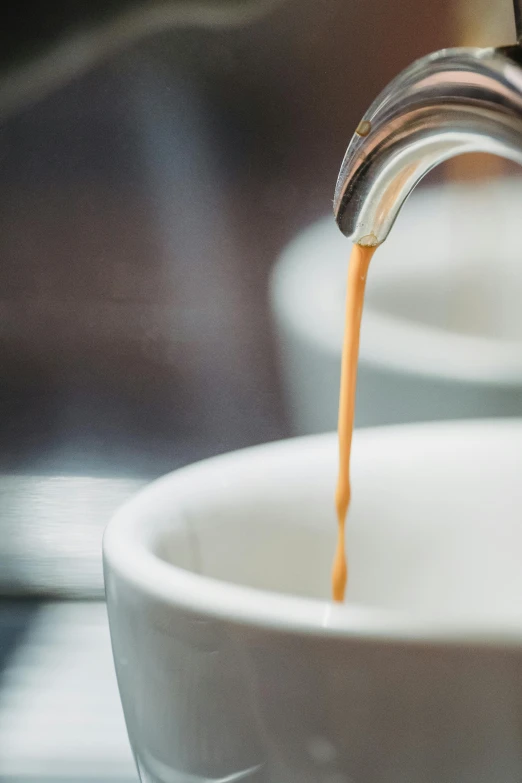 an orange liquid is poured into a white cup