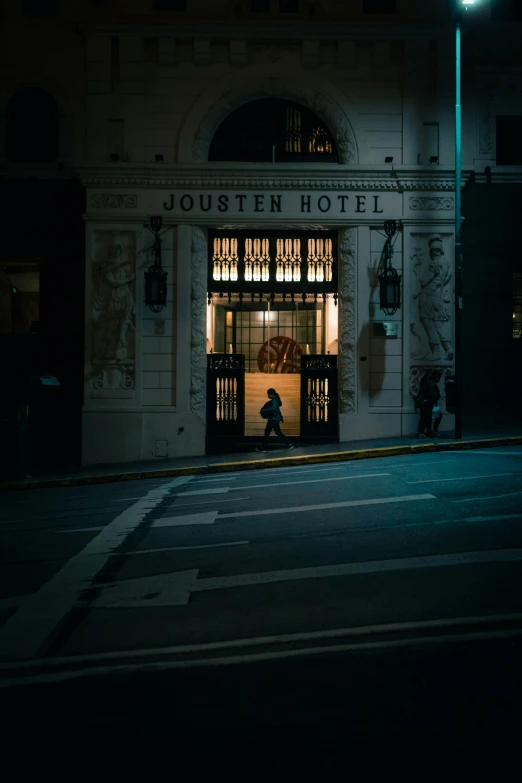 the dark street in front of a building has lights on