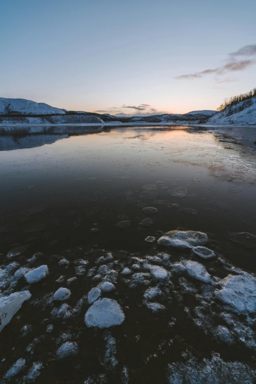 a pond is covered in ice at sunset