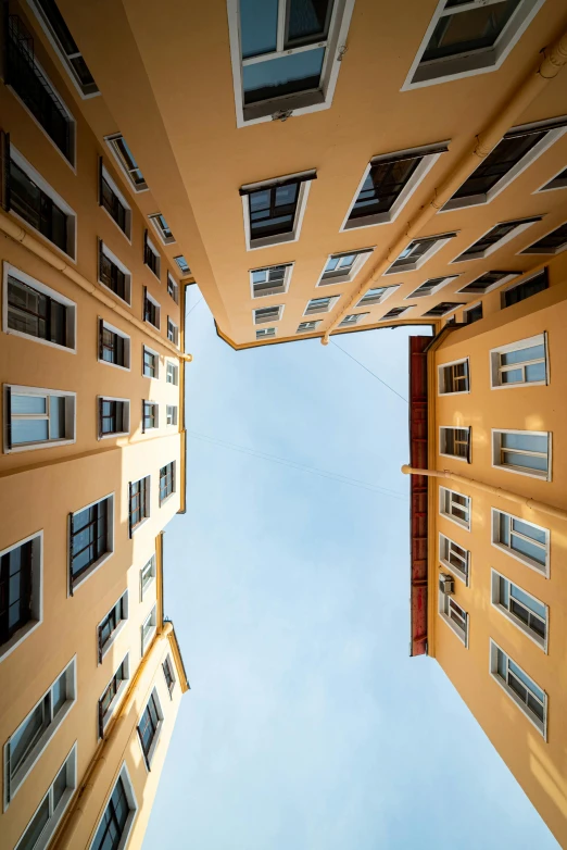 the view up from an apartment building looking up into a blue sky