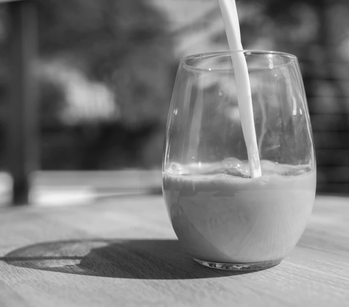 glass filled with liquid on wooden table outside