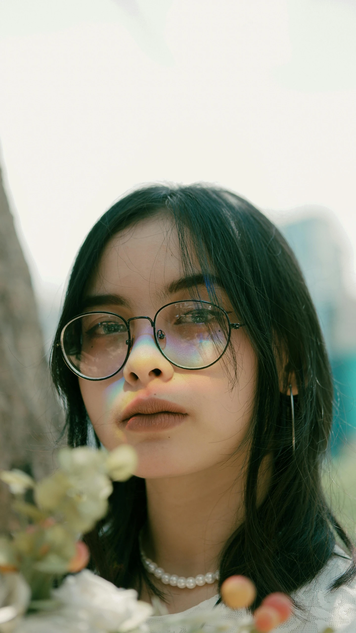 a woman standing next to a tree wearing glasses