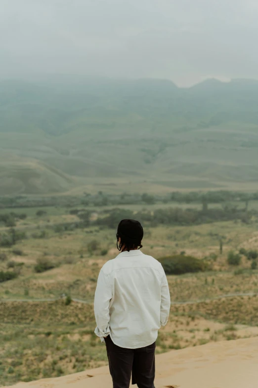 a man with his back to the camera looks out into the countryside