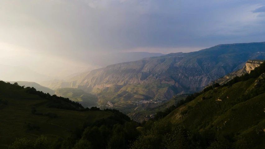 the green hilly mountains are covered in fog