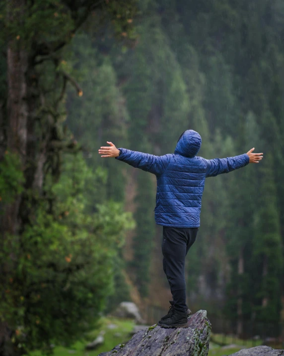 a man is standing on a rock with his arms spread wide