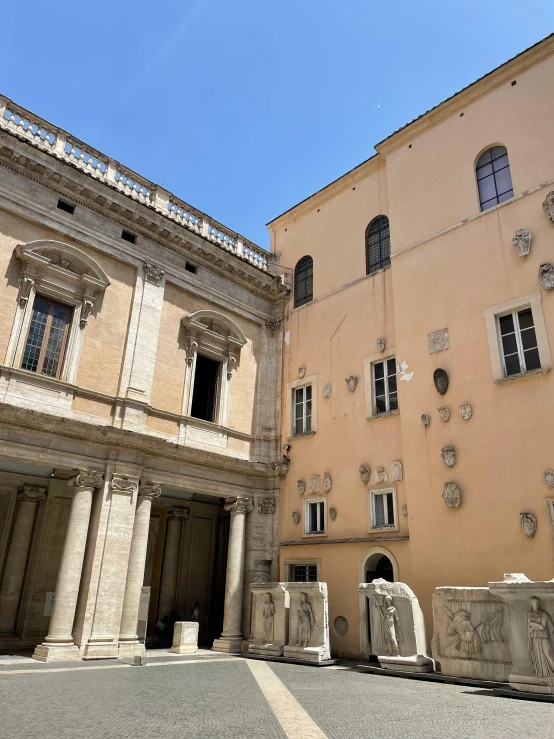 a very large tan building with some statues near by