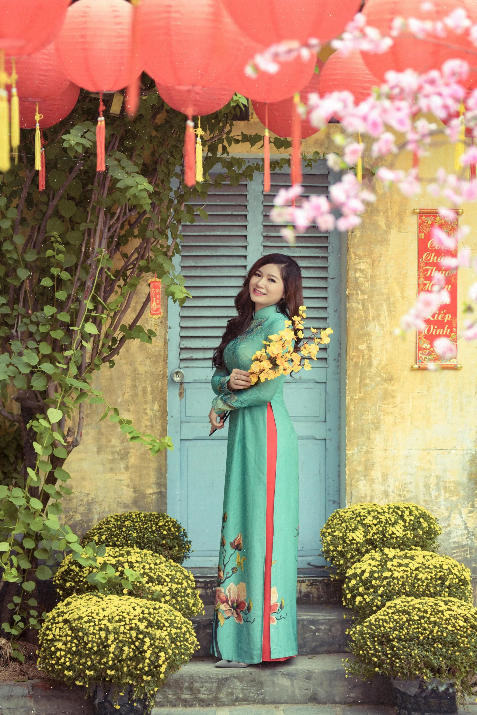 a woman wearing a long green dress holds a flower and looks into the distance