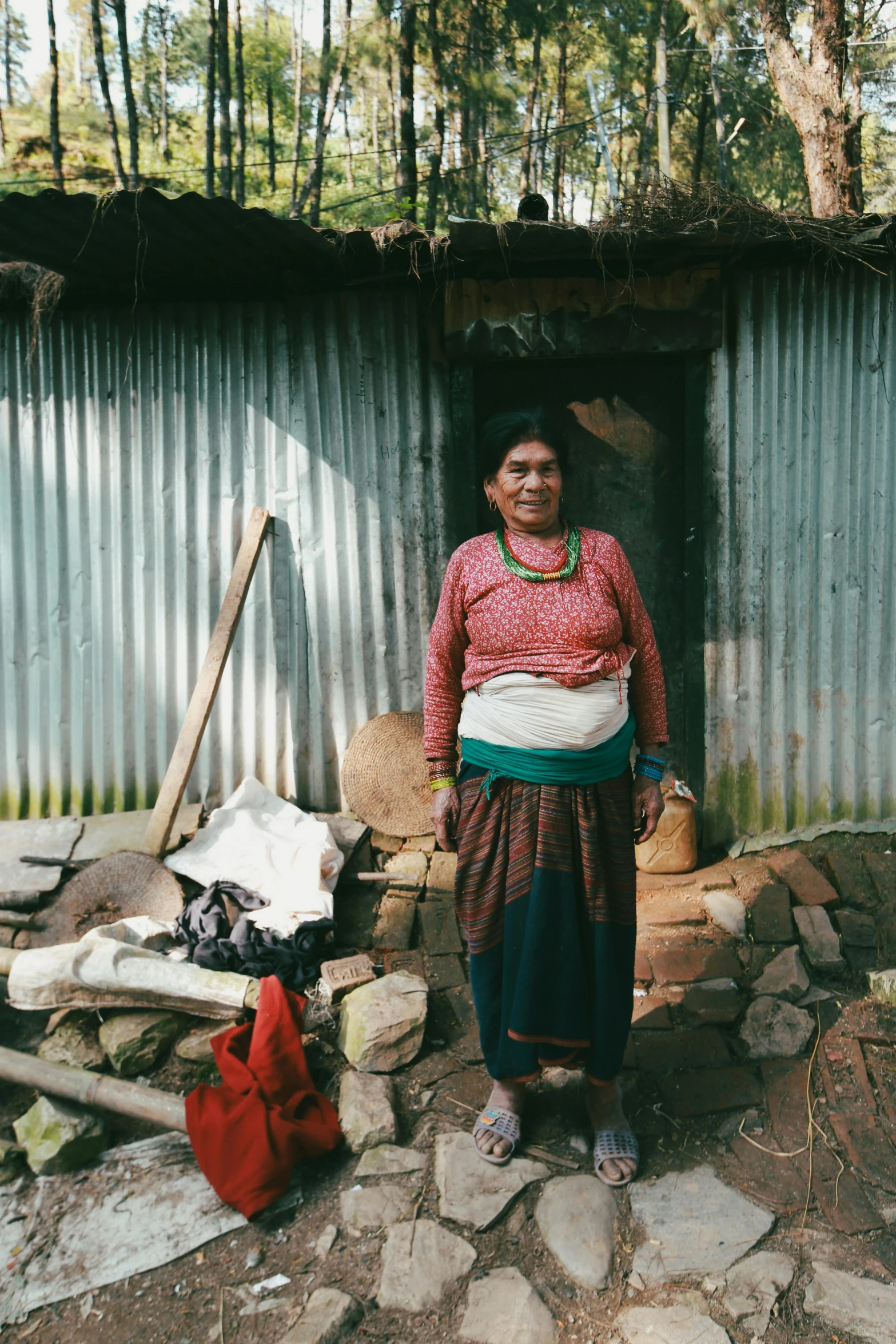 a woman in an ethnic dress standing outside a hut