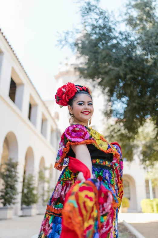 a woman in a colorful dress stands in the street