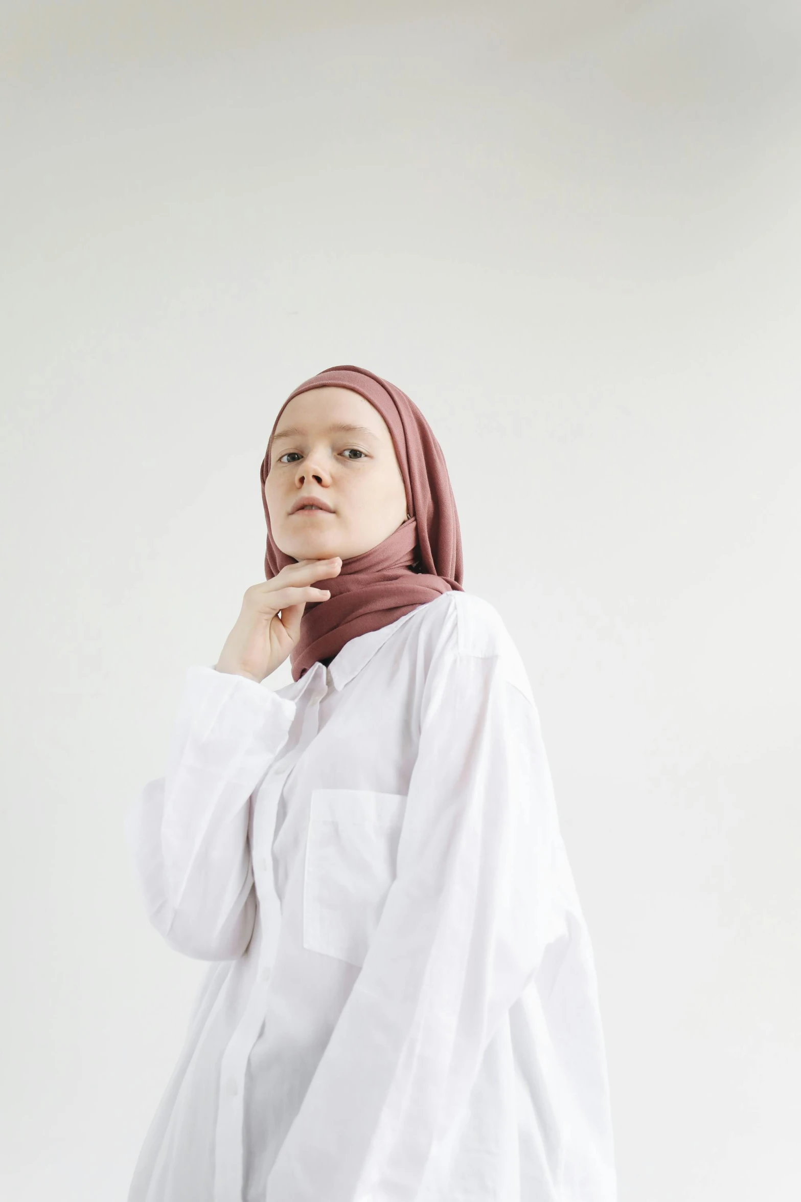 woman in white shirt with long hair standing against a wall