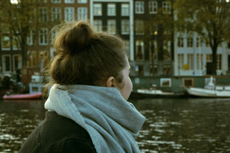 a woman wearing a scarf standing on top of a lake