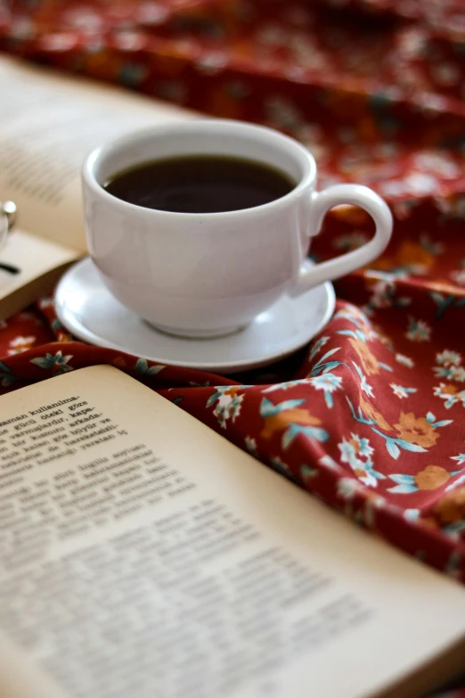 an open book and some kind of cup on a bed