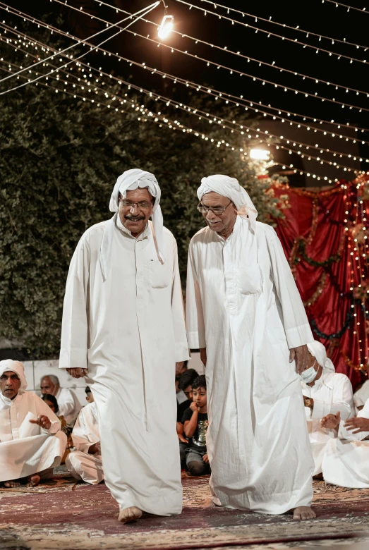 two men are dressed in white walking side by side