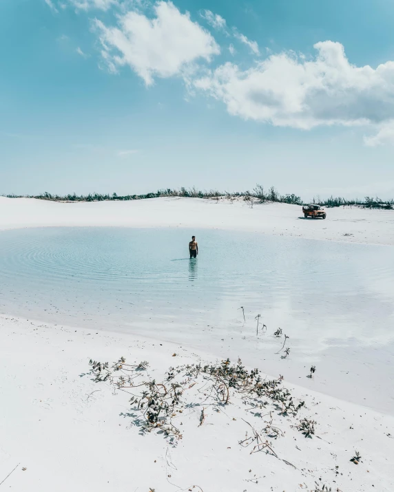 a lone man wading through the shallow water of an ocean