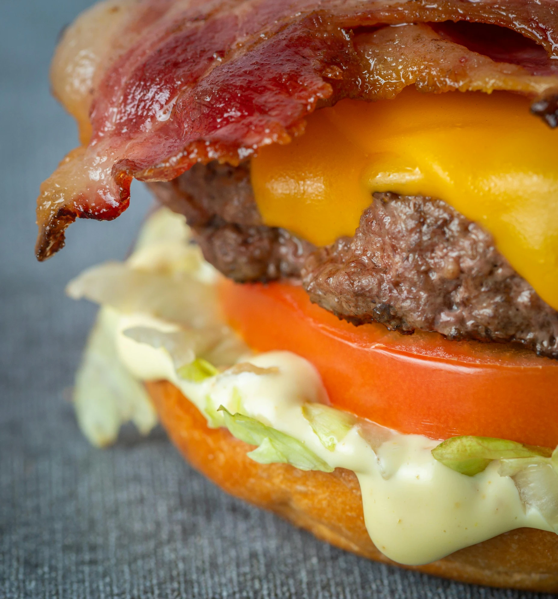 a bacon cheeseburger with tomato and lettuce