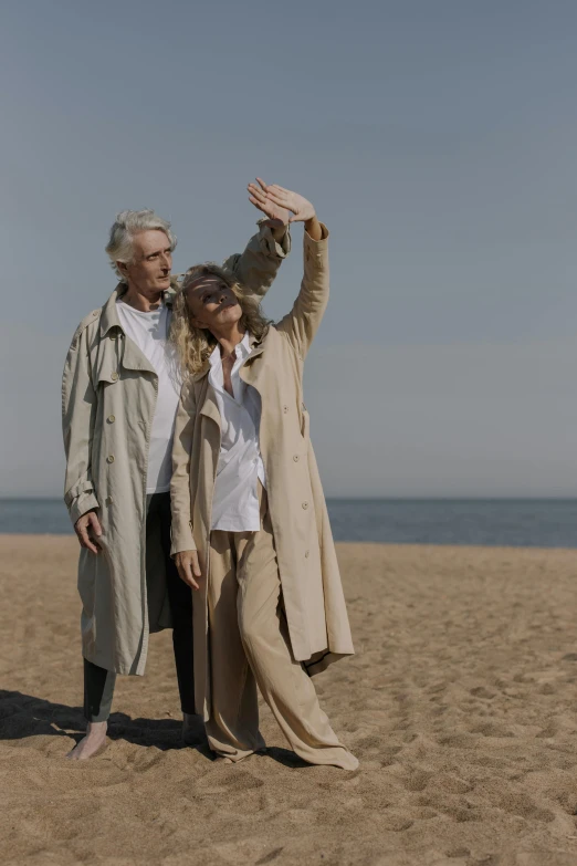 a couple of people standing on top of a sandy beach