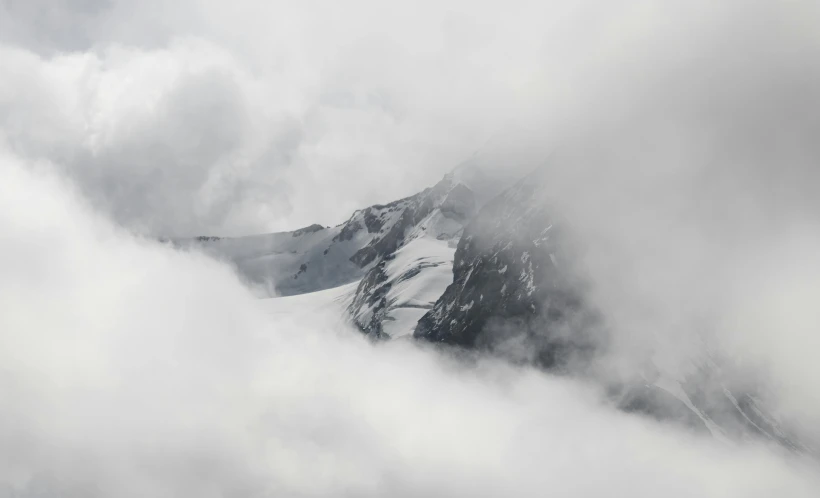 a mountains covered in snow and cloud on a cloudy day