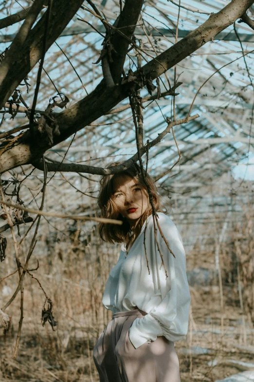 a woman standing under a tree wearing a white top