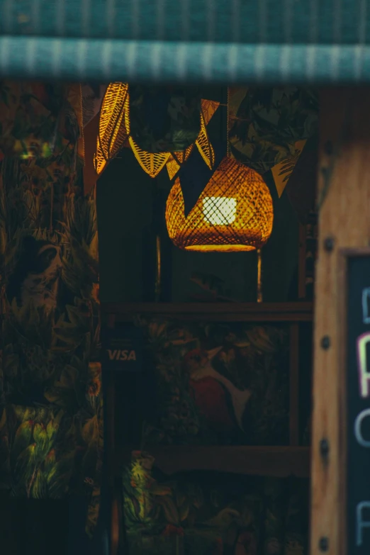 a yellow basket light fixture hangs above a wooden table