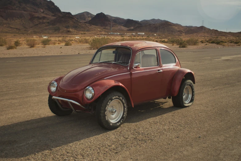 a small red beetle is parked in the desert