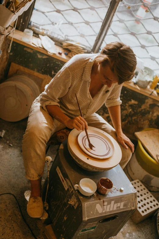 woman painting a piece of pottery in a workshop