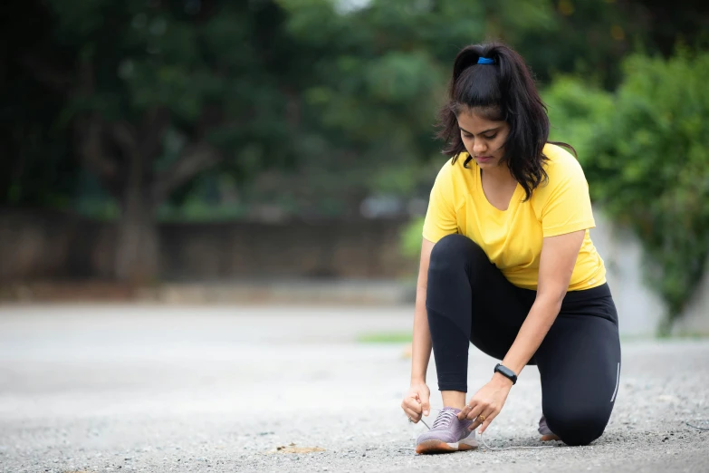 a woman is crouched down and tying up her sneakers