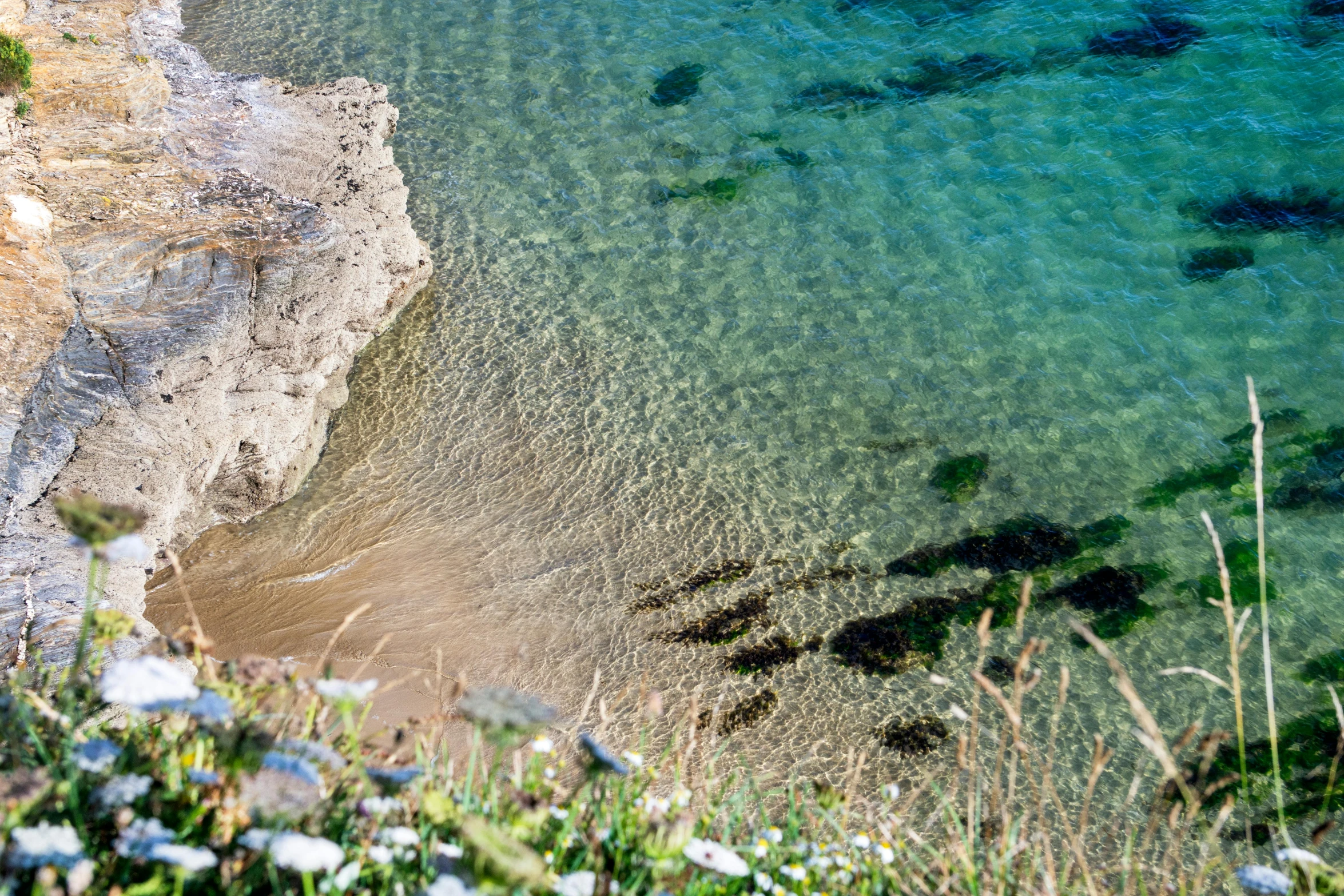 a beach shore with clear water next to a sandy shoreline