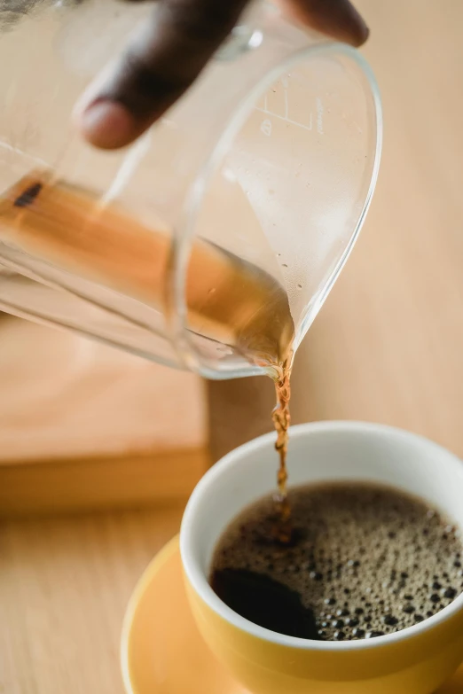 someone pours some coffee into a cup