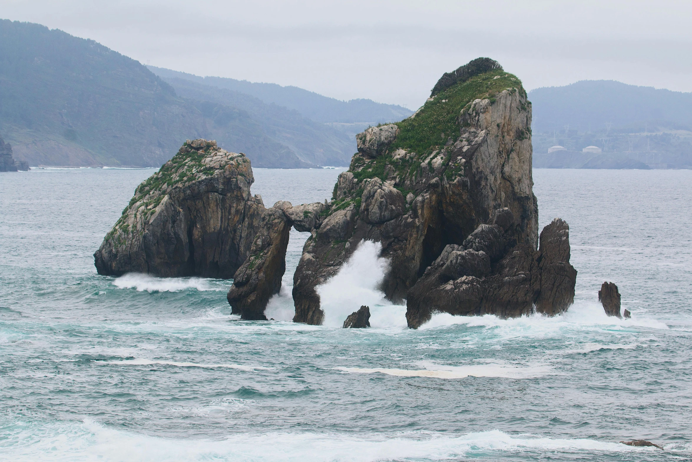 a rocky ocean shore surrounded by rough blue water