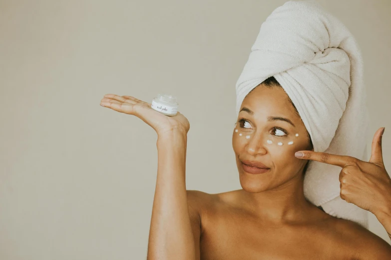 a woman is holding up her left hand and touching the skin cream