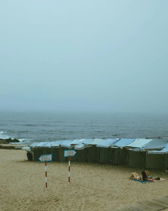 a row of shelters on a beach next to water