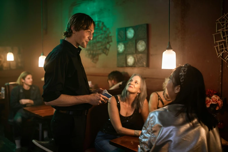 a man stands near some women at a bar