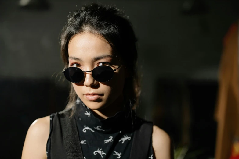 a woman with black sunglasses with an animal print shirt and a necklace