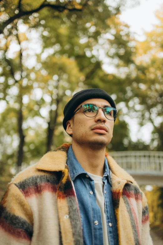 a young man with his head turned wearing glasses and a sweater