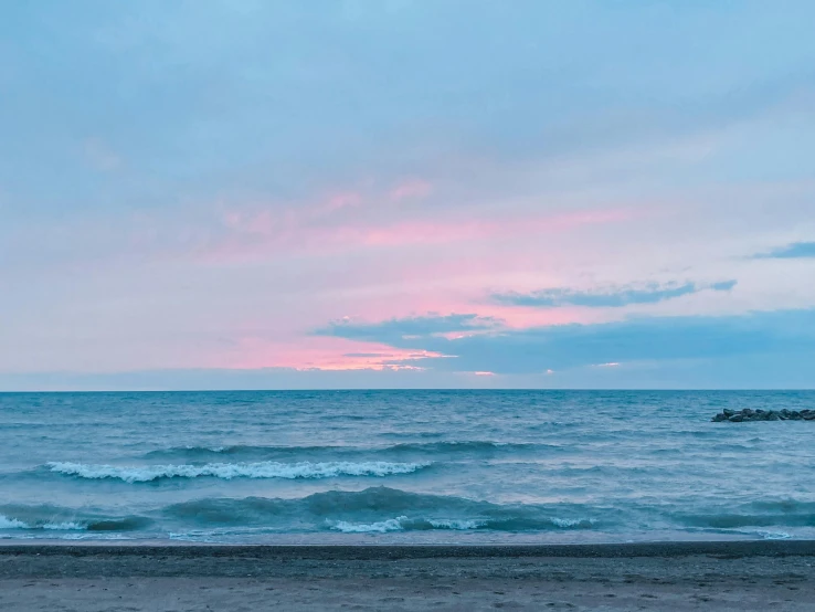 the waves crash in the foreground as the sky shines bright