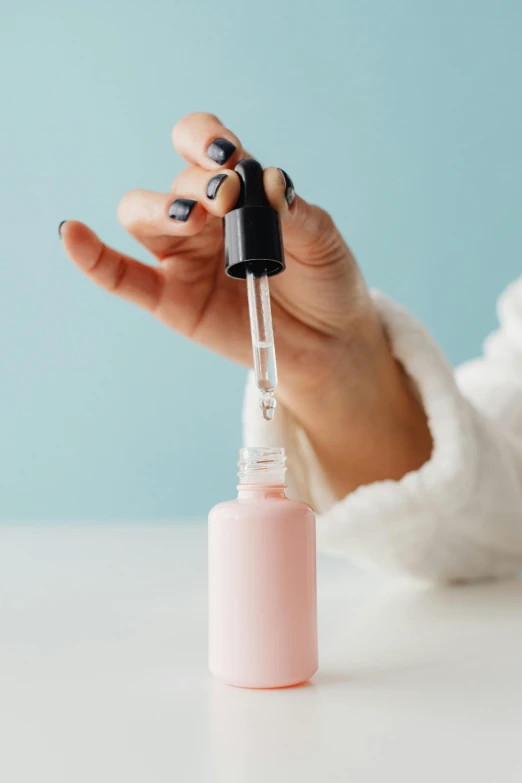 a hand holding up a small pink bottle