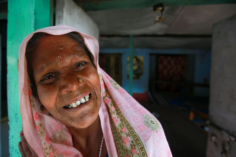 a smiling woman wearing a pink sari
