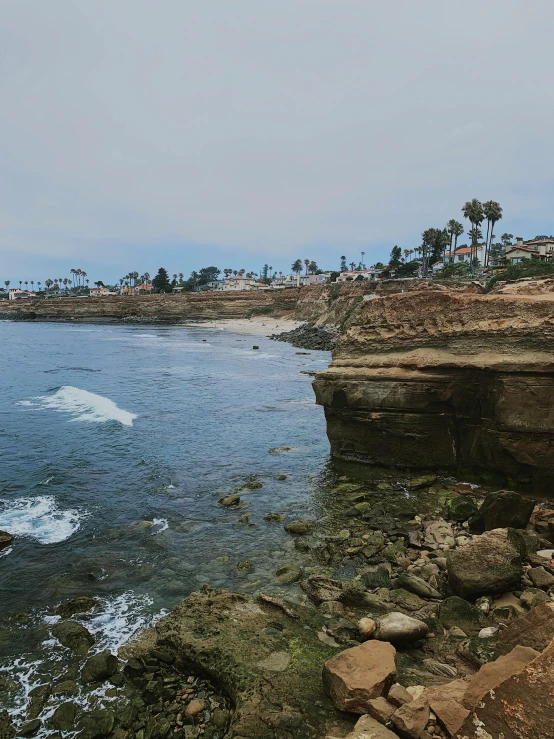 two men are sitting on rocks near the ocean