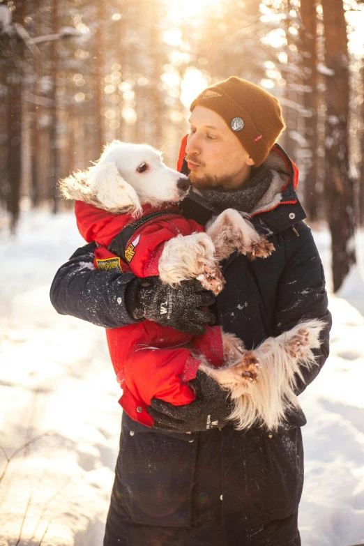 a person holding a small dog while standing in the snow