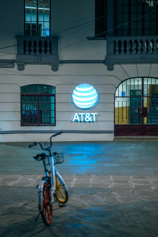 the front of a building at night with a bicycle parked by